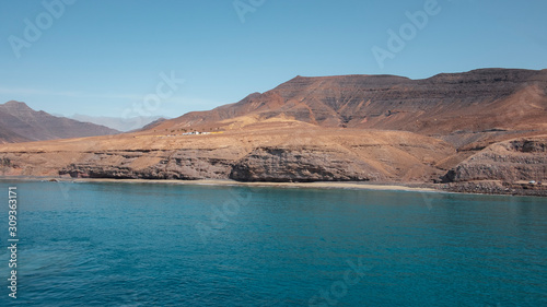 Approaching Fuerteventura island at its most southern point  at Morro Jable with the display of the solitary cliffs and arid mountains behind  part of the Parque Natural Jandia  Canary Islands  Spain