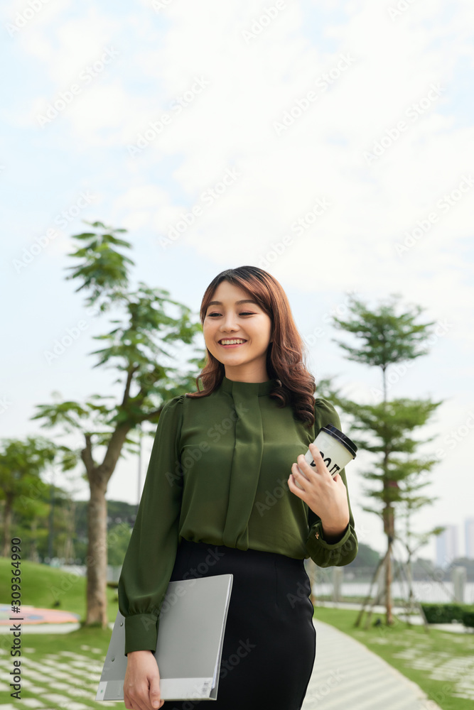 Asian woman taking a coffee break at city park. Beautiful young businesswoman portrait. Asian woman taking a coffee break at city park. Beautiful young businesswoman portrait.