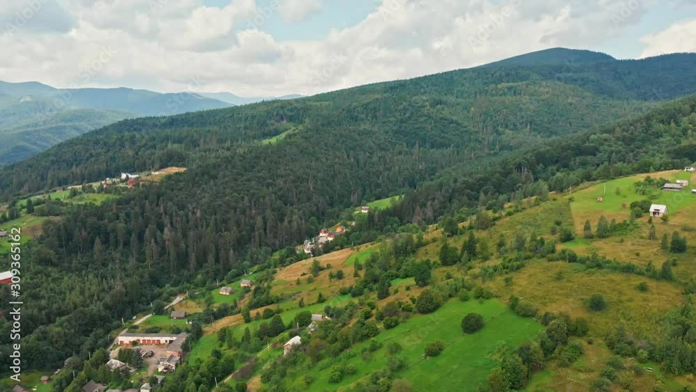 Aerial view of mountain range, road, and fir forest with village on background. Aerial view of mountain range, road, and fir forest with village on background.