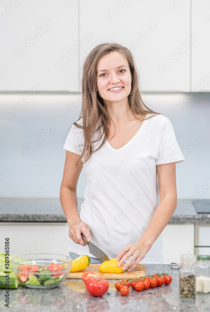 Smiling young woman cooking in the kitchen at home Smiling young woman cooking in the kitchen at home