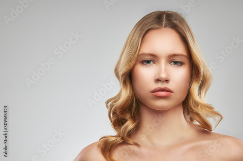 Gorgeous caucasian blond woman with makeup posing in studio and looking at camera.