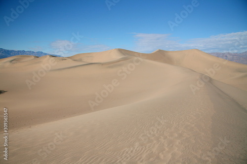 Massive sand dunes in Death Valley National Park desert in the winter golden and blue sky