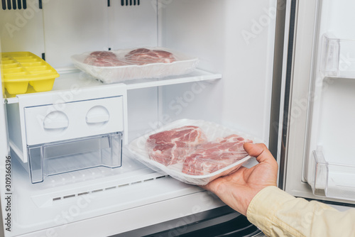 cropped view of man taking out frozen meat from freezer photo