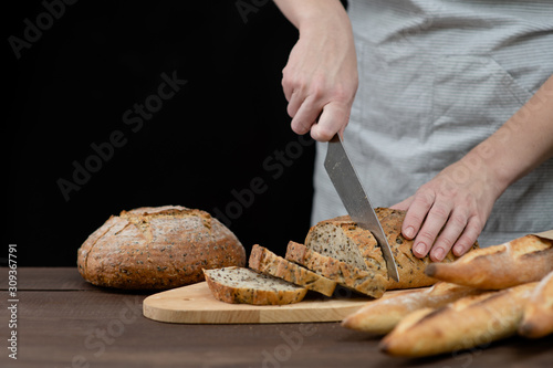Woman slicing home-made bread. Isolated on dark background. Empty space for text