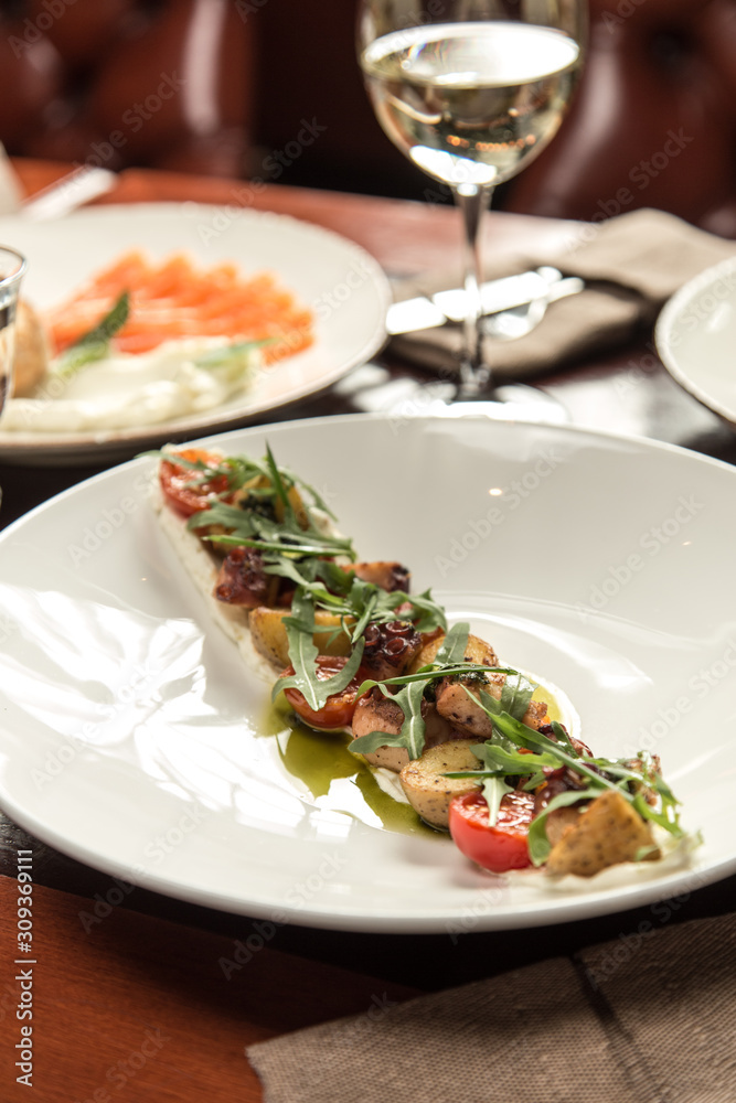 octopus salad with potatoes and cherry tomatoes on wooden table at restaurant octopus salad with potatoes and cherry tomatoes on wooden table at restaurant