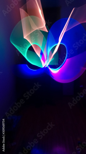 Obraz na płótnie Boy playing in his room in dark with multicolored light stick, creating lighting shapes