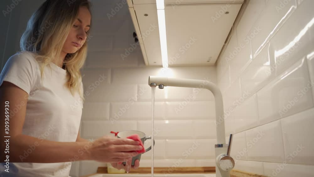 Attractive young woman is washing dishes while doing cleaning at home Attractive young woman is washing dishes while doing cleaning at home
