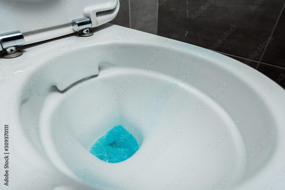 close up view of blue liquid detergent in ceramic clean toilet bowl in modern restroom with grey tile close up view of blue liquid detergent in ceramic clean toilet bowl in modern restroom with grey tile