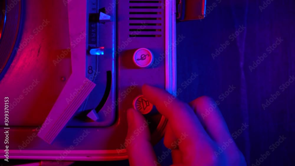 Male hand turns on music on a vintage record player for vinyl records. Close-up: volume up on a retro player