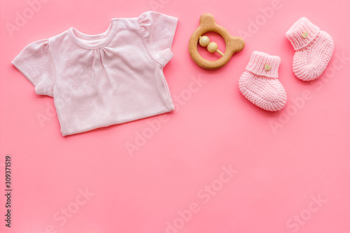 Baby background - pink color. Clothes, booties and accessories for newborn girl on pink table top-down frame copy space