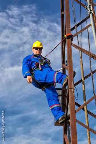 Electrician with safety belt and yellow helmet on electric pole