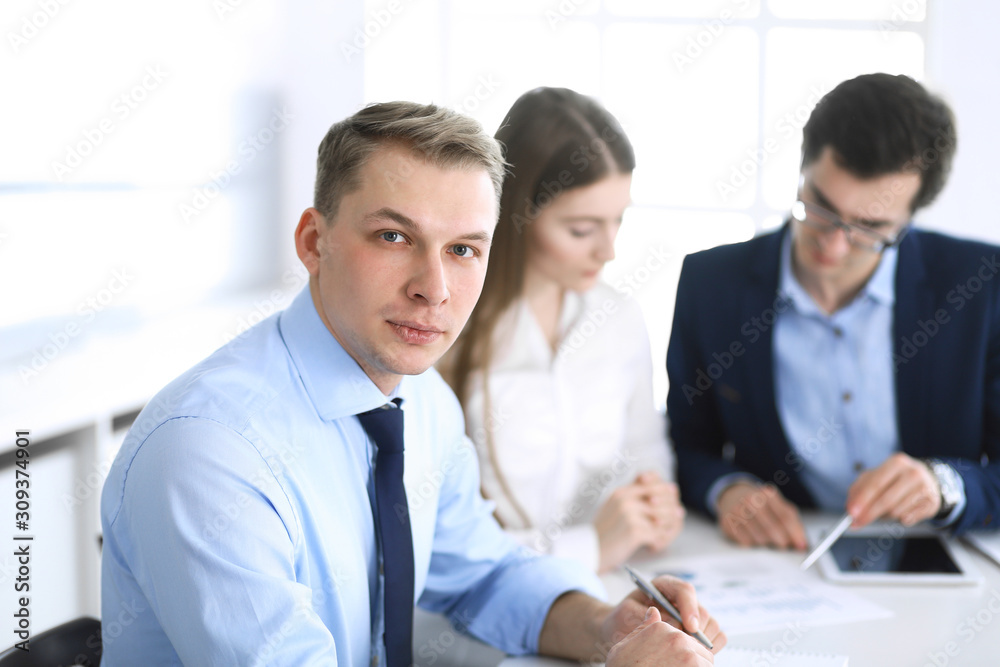 Group of business people discussing questions at meeting in modern office. Headshot of businessman at negotiation. Teamwork, partnership and business concept Group of business people discussing questions at meeting in modern office. Headshot of businessman at negotiation. Teamwork, partnership and business concept