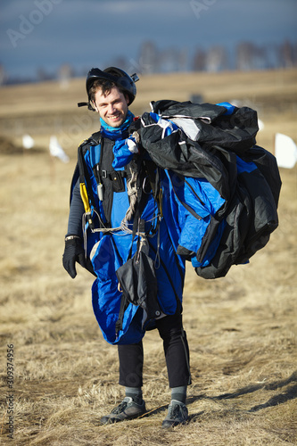 Young skydiver in wingsuit smiles posing for a photo shoot after performing a parachute jump, close-up. photo