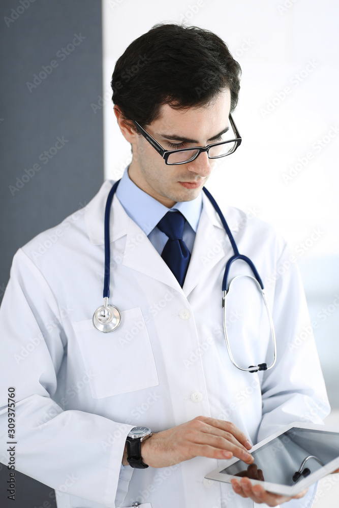 Doctor man using tablet computer for network research or virtual disease treatment. Perfect medical service in clinic. Modern medicine, medic data and healthcare concepts Doctor man using tablet computer for network research or virtual disease treatment. Perfect medical service in clinic. Modern medicine, medic data and healthcare concepts