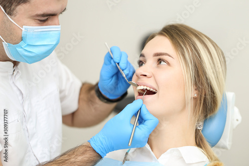 Blond female sits in dentist chair and undergo dentist checkup