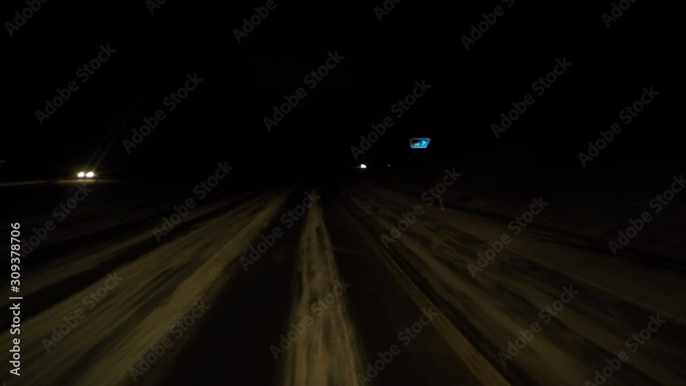 Car driving on snowy empty highway without lamps at night. Car driving on snowy empty highway without lamps at night.