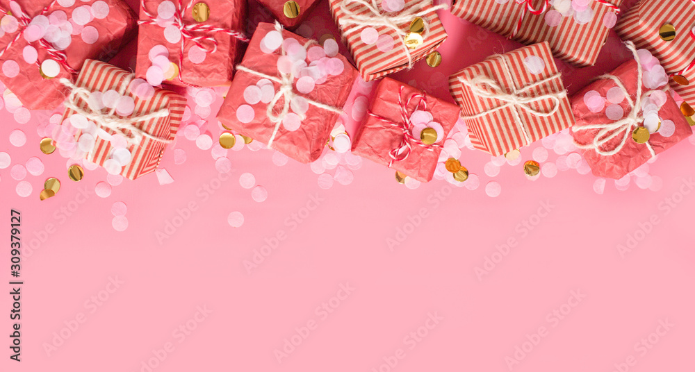 Christmas background. Golden gift or present boxes and star confetti on pink top view.