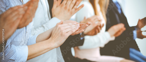 Business people clapping and applause at meeting or conference, close-up of hands. Group of unknown businessmen and women in modern white office. Success teamwork or corporate coaching concept photo