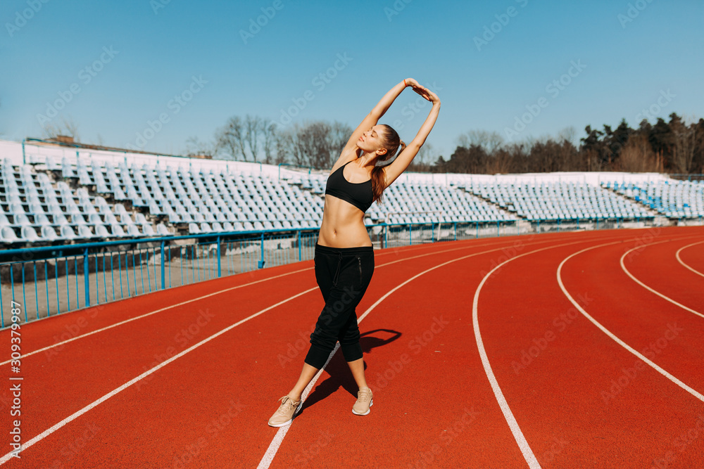 Obraz premium young fitness woman runner warm up before running on track. Morning exercises at summer