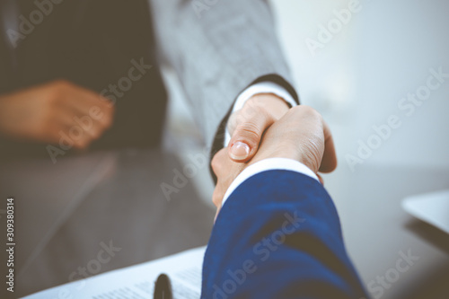 Businessman and business woman shaking hands to each other above signed contract. Success at negotiation and agreement concept