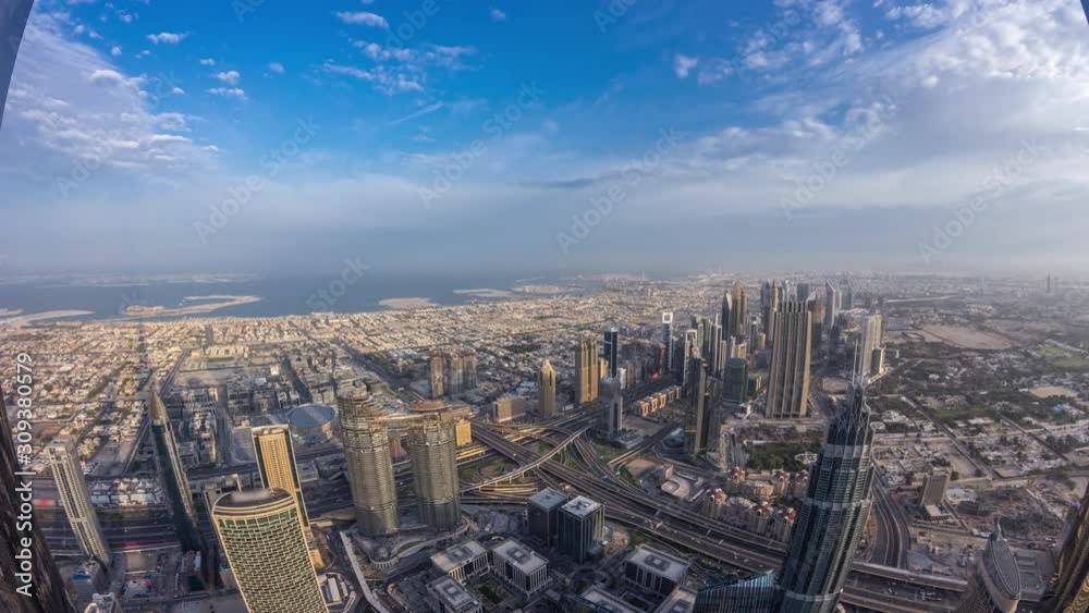 Downtown and and financial district in Dubai night to day transition timelapse. Cloudy sky and traffic on highway. Aerial view with towers and skyscrapers from Burj Khalifa viewpoint.