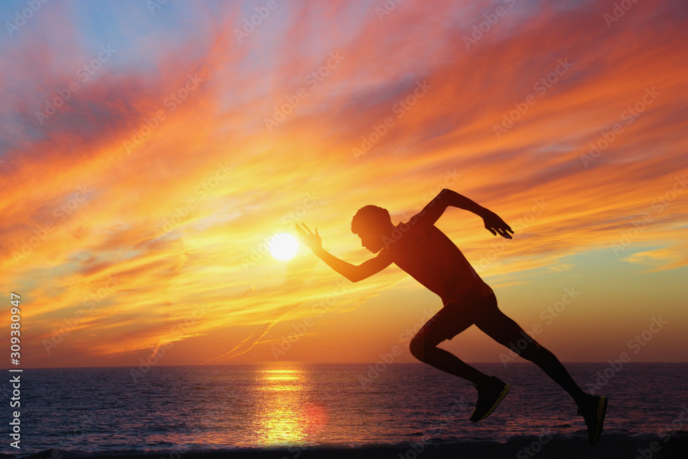 A man running on the beach at sunset. - Image