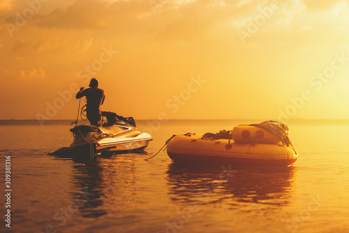 Banana boat float with jet ski in the sea with sunset.
