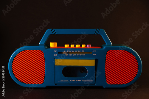 Old red-blue tape recorder on cassettes on a black background
