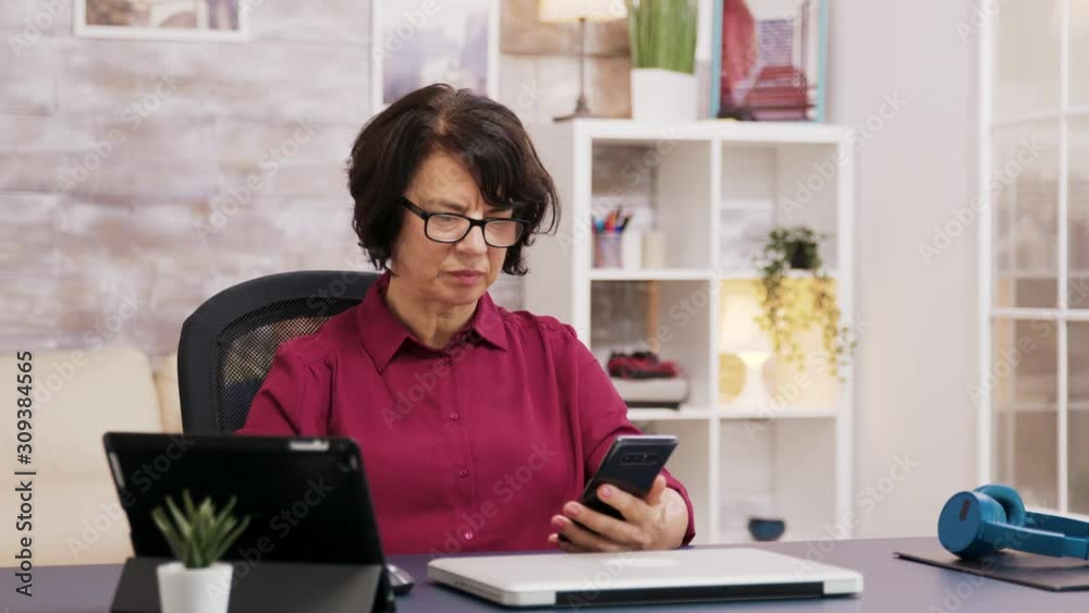 Elderly woman with glasses using tablet and phone Elderly woman with glasses using tablet and phone