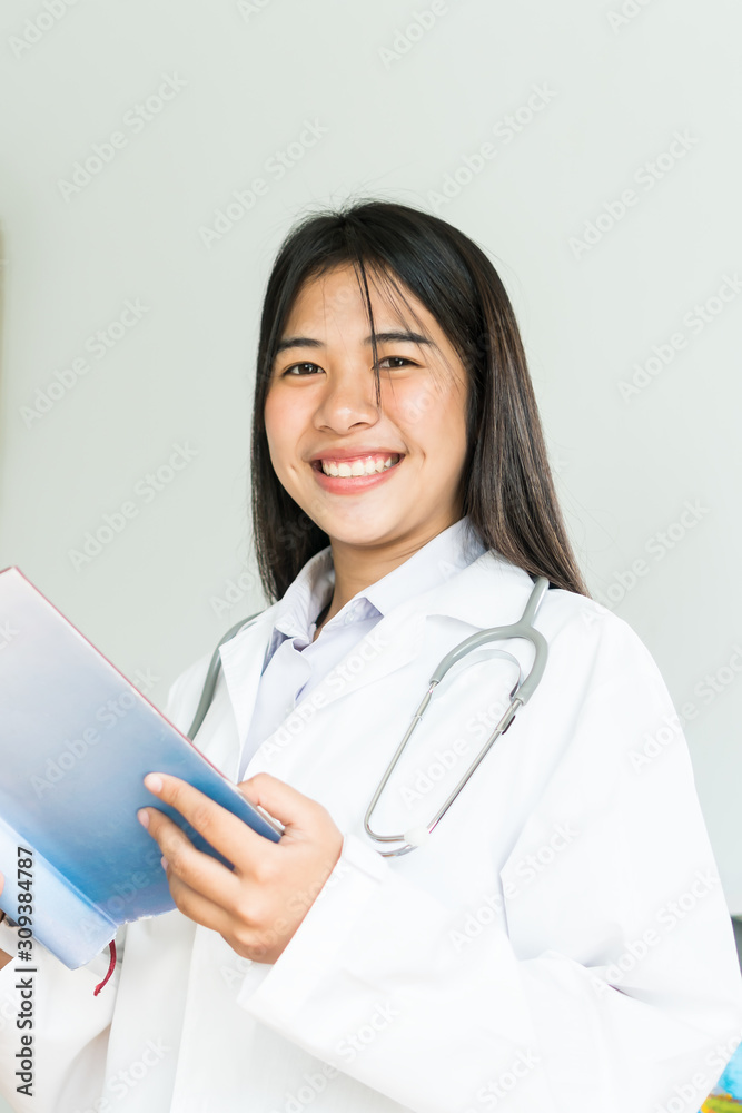 student medicine or young Asian female doctor holding textbook for learning in medical treatment patient, white uniform, smiling in healthcare at hospital, post for advertising doctor's career concept