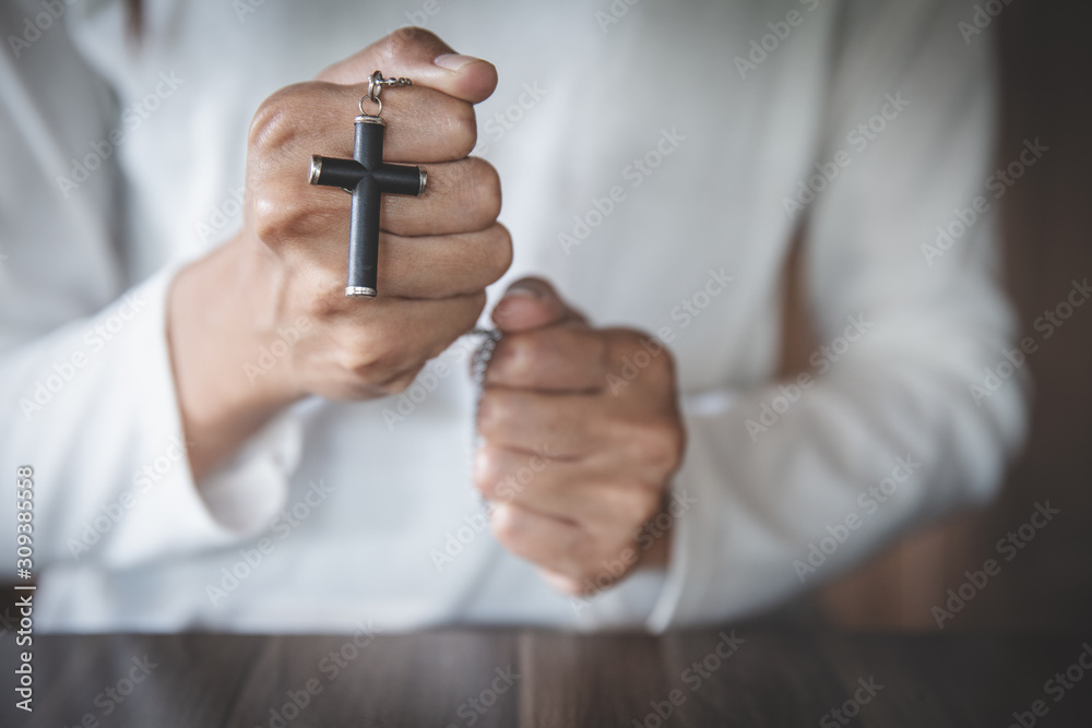 Fototapeta premium A cross in the hands of a young woman blessing on the scriptures from God with the power and power of holiness, which brings luck and the power of religion, faith, worship, Christian thought.