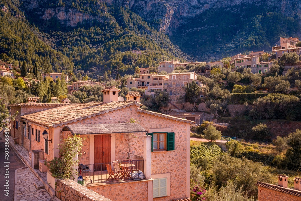 Obraz premium Typical Spanish houses in Valldemossa town, surrounded by mountains and trees, sunny day,, Mallorca, Spain.