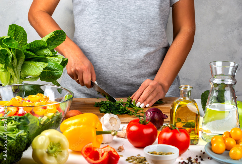 Woman cuts greens and cooking salad in the kitchen. Healthy diet concept. Woman cuts greens and cooking salad in the kitchen. Healthy diet concept.