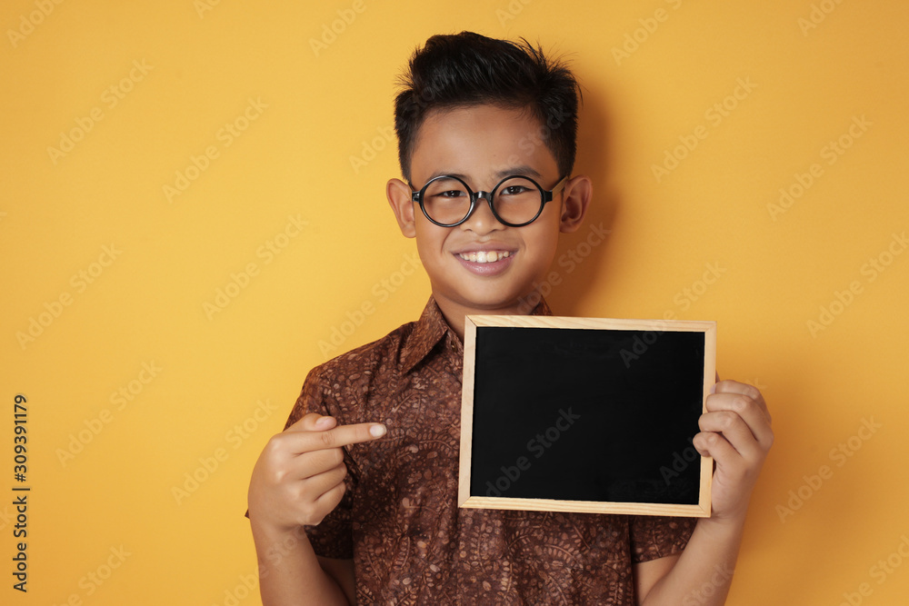 Smart Asian Boy Smiling at Camera and Showing Empty Blackboard Smart Asian Boy Smiling at Camera and Showing Empty Blackboard