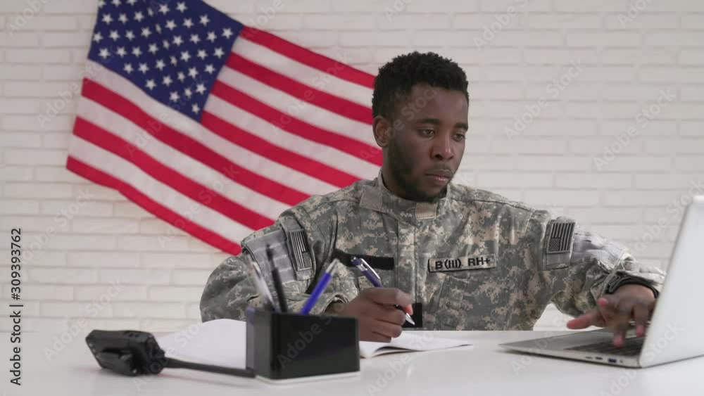 Afro-american soldier in uniform working seriously in office