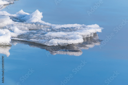 Close-up of frozen cracked ice and snow on river water in spring or winter time