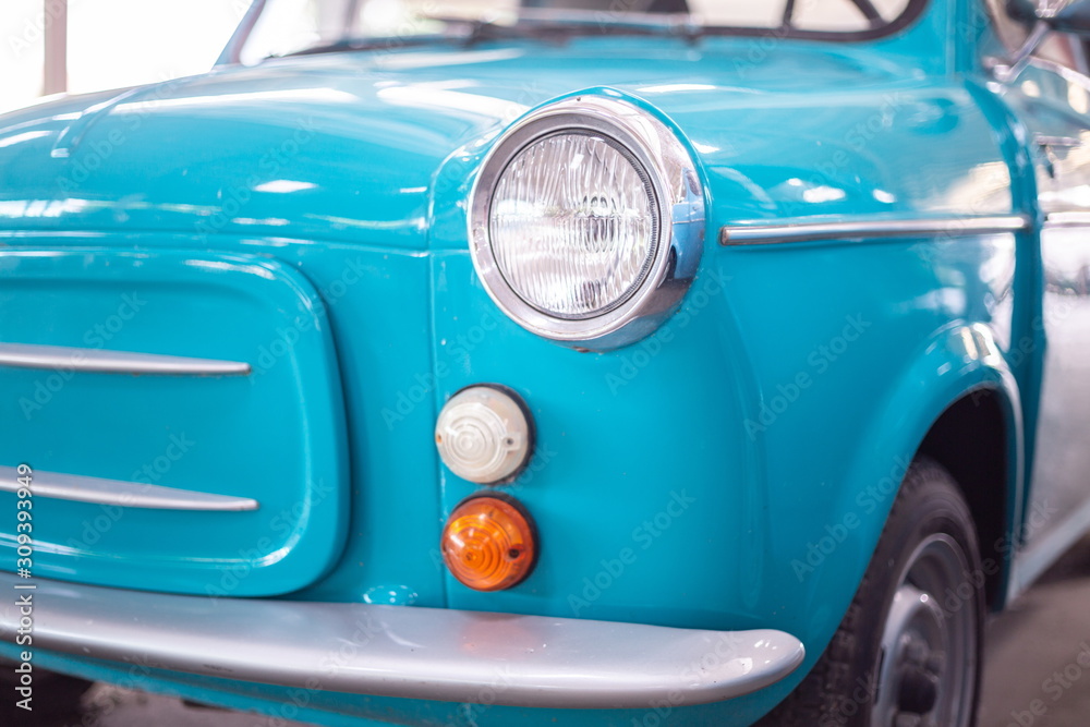 close up headlight of blue vintage car in garage .
