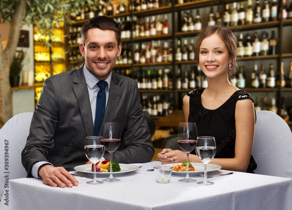 leisure and luxury concept - smiling couple with food and wine over restaurant or wine bar background