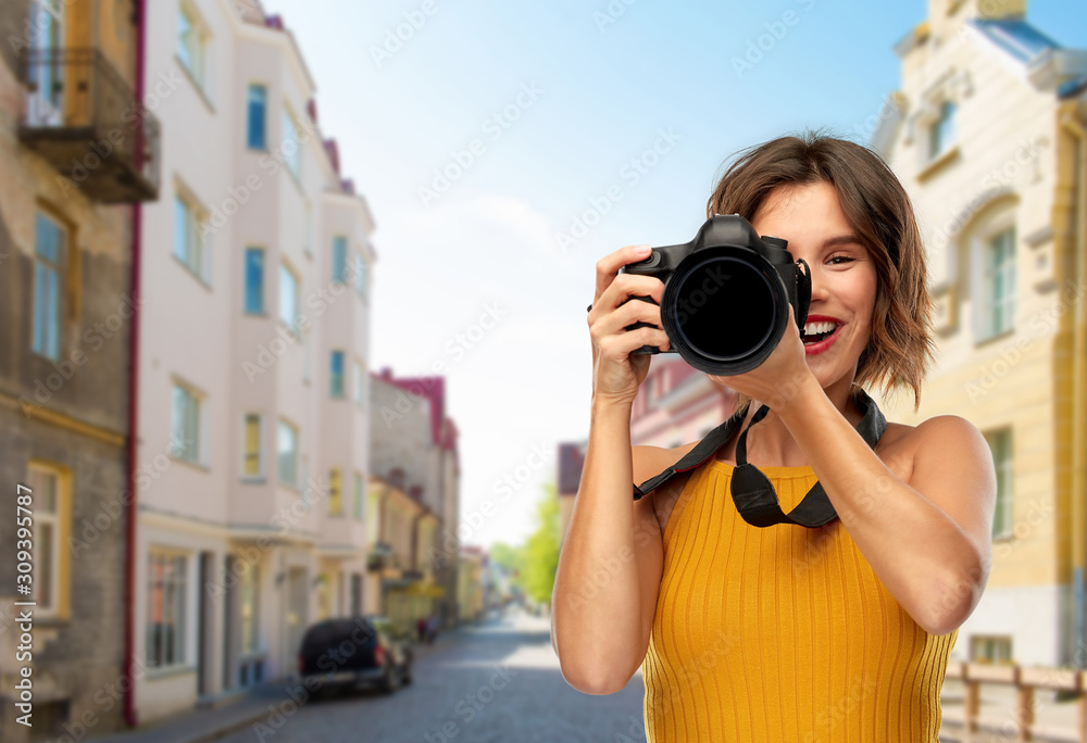 travel, tourism and photography concept - happy woman photographer in mustard yellow top with digital camera over european city street background