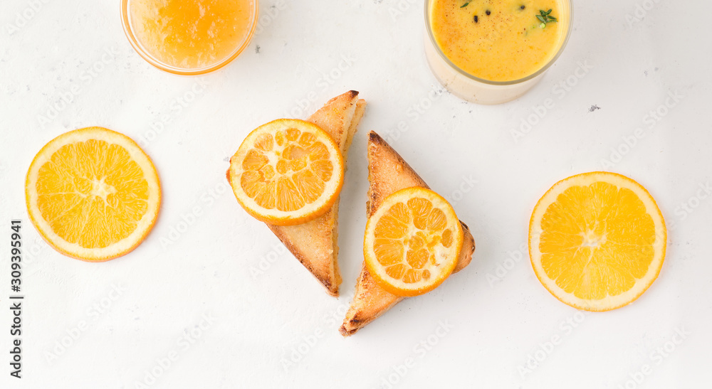 toasts with jam on a white plate next to slices of orange toasts with jam on a white plate next to slices of orange