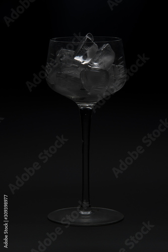 A wine glass with ice on a black background.