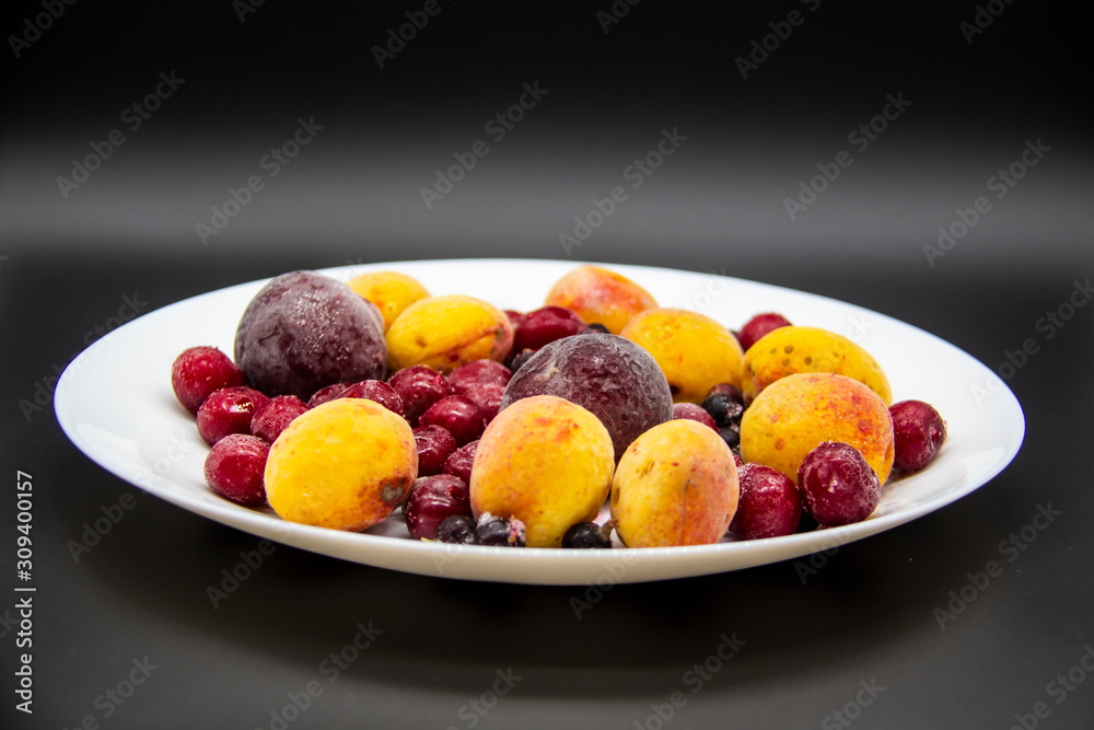 A Berry mix from frozen currant, apricot, plum, cherry on the white plate. Frozen Berries from freezer. A background with frozen plum, currant, apricot and cherry. A healthy Berries on the background A Berry mix from frozen currant, apricot, plum, cherry on the white plate. Frozen Berries from freezer. A background with frozen plum, currant, apricot and cherry. A healthy Berries on the background
