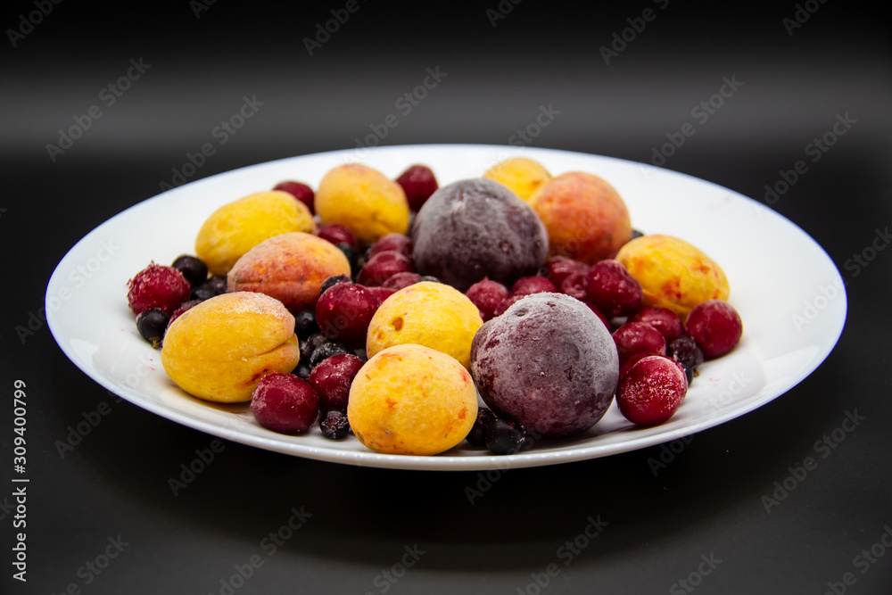 A Berry mix from frozen currant, apricot, plum, cherry on the white plate. Frozen Berries from freezer. A background with frozen plum, currant, apricot and cherry. A healthy Berries on the background A Berry mix from frozen currant, apricot, plum, cherry on the white plate. Frozen Berries from freezer. A background with frozen plum, currant, apricot and cherry. A healthy Berries on the background