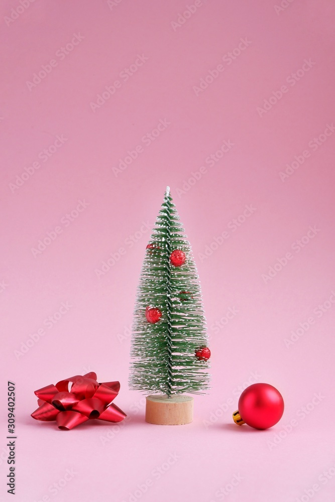 Chrismas decorative plastic fir tree on pink background. New year festive vertical backdrop, holiday decorations. Creative concept Christmas holiday. Chrismas decorative plastic fir tree on pink background. New year festive vertical backdrop, holiday decorations. Creative concept Christmas holiday.