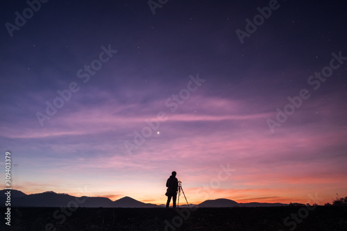 Photographer standing with cloudy twilight sky in the morning