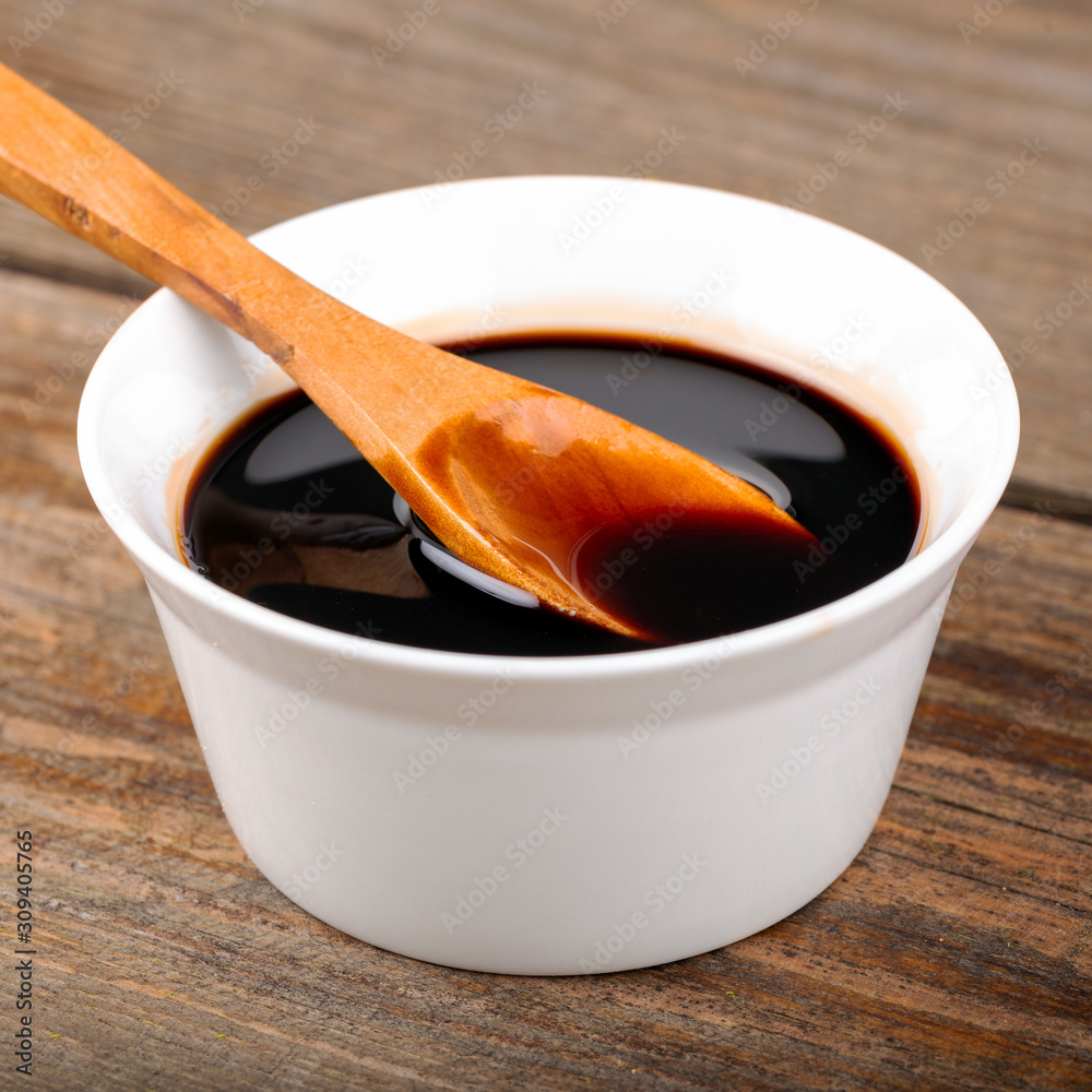 Homemade pomegranate sauce in a bowl with a spoon, fresh open pomegranate on a wooden background Homemade pomegranate sauce in a bowl with a spoon, fresh open pomegranate on a wooden background