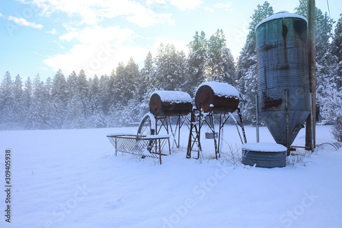 Winter old American Country landscape with rustic houses, cars and fences covered in snow. © Iriana Shiyan