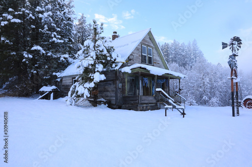 Winter old American Country landscape with rustic houses, cars and fences covered in snow.