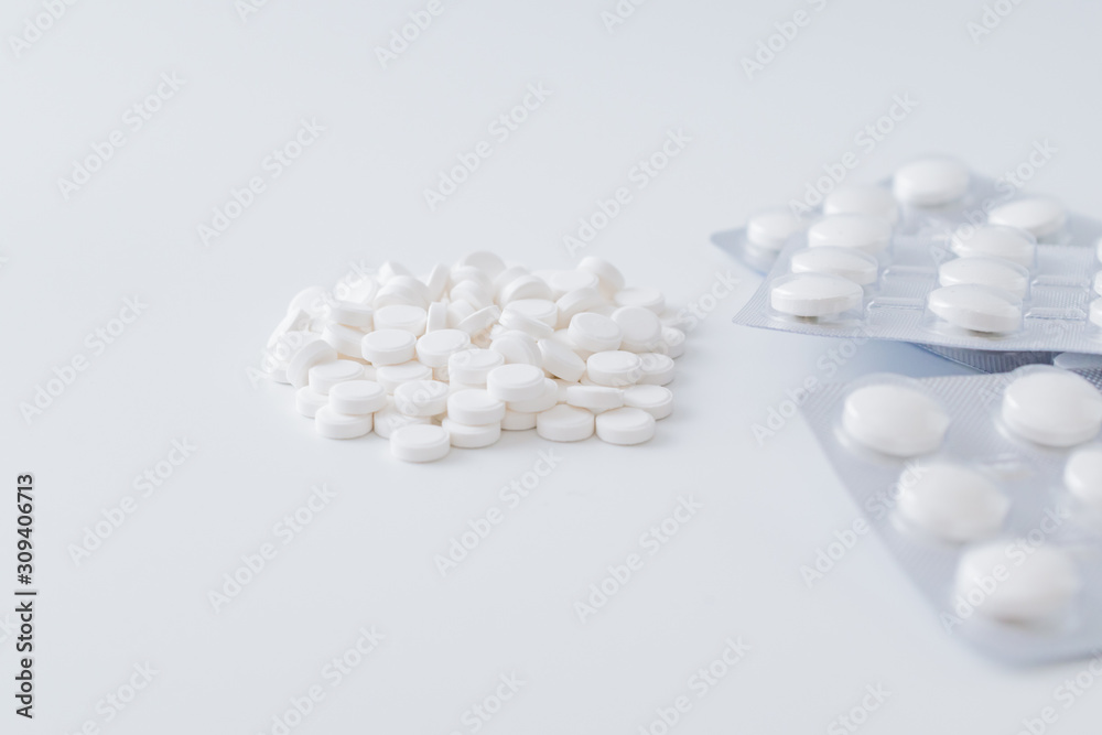 White pills in a blister and whitek pills on a light background. Medical pharmacy concept