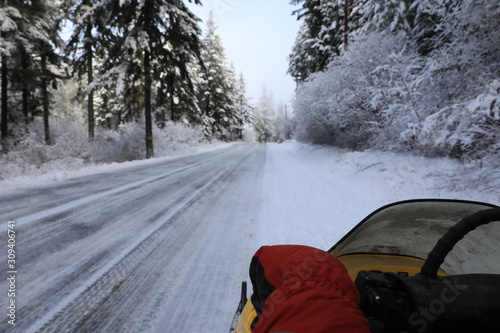 Man riding snomobile in the mountains near cabin houses and trees. photo